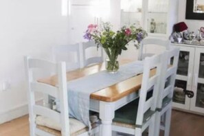 A dining table with a vase of flowers, surrounded by white chairs. - Coastal Hideaway - Sleeps 4 & Free Parking (Dublin)