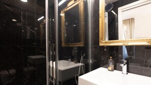 A modern bathroom with a glass-enclosed shower, a white sink, and a gold-framed mirror. - Superior Double Room with AC (Roma)