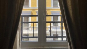 A window with two white doors and a view of a yellow building with balconies. - Superior Double Room with AC (Roma)