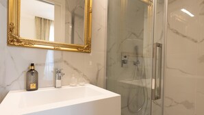 A bathroom with a white sink, gold-framed mirror, and a glass-enclosed shower. - De Vince Suites   Luxury Rooms   King Executive (Roma)