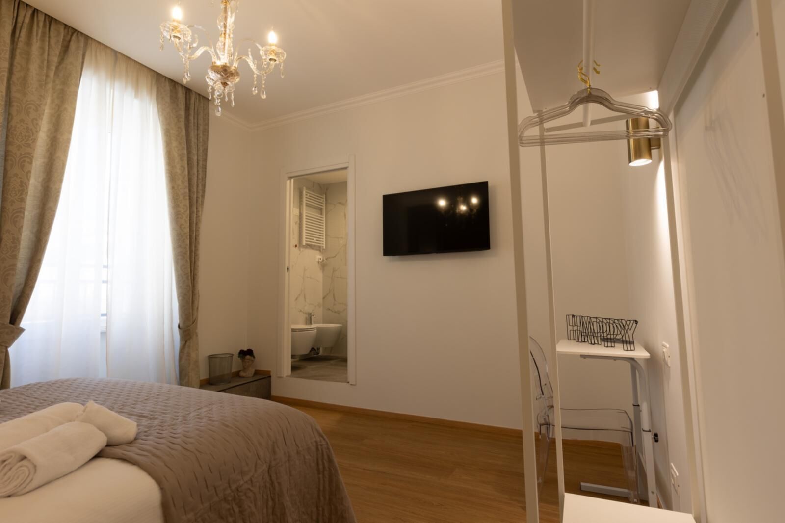 Un dormitorio con cama, televisor, espejo y vestidor.