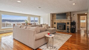 Amplia sala de estar con un sofá modular grande, una chimenea y vistas al exterior.