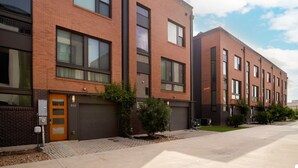 A modern brick building with multiple garage doors, a small entrance with a door number 303, and a sidewalk with a few small trees. - Stylish Pearl District Stay - Relax, Dine & Explore (San Antonio)