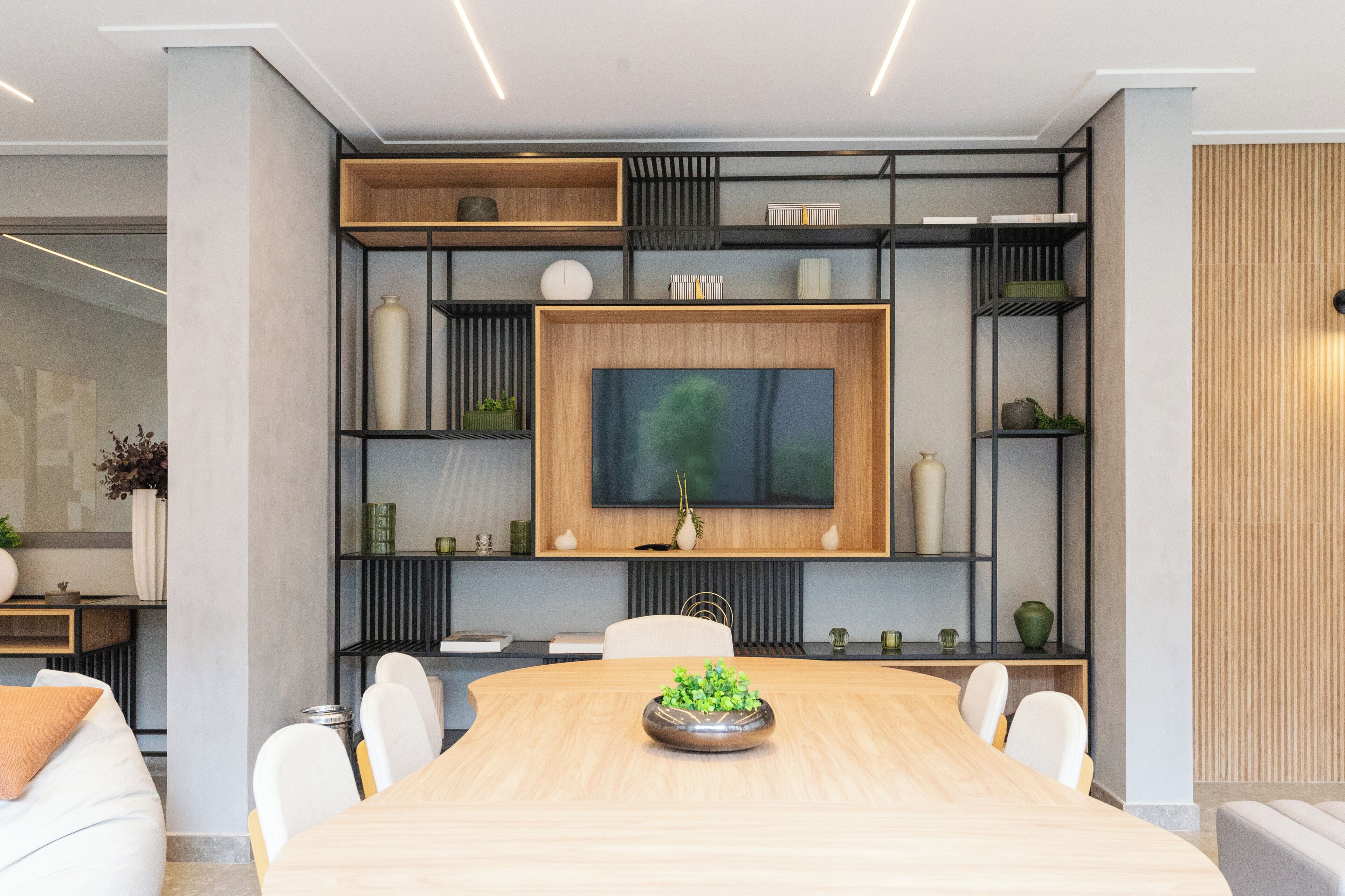 A modern dining area with a wooden table, white chairs, and a central decorative bowl.