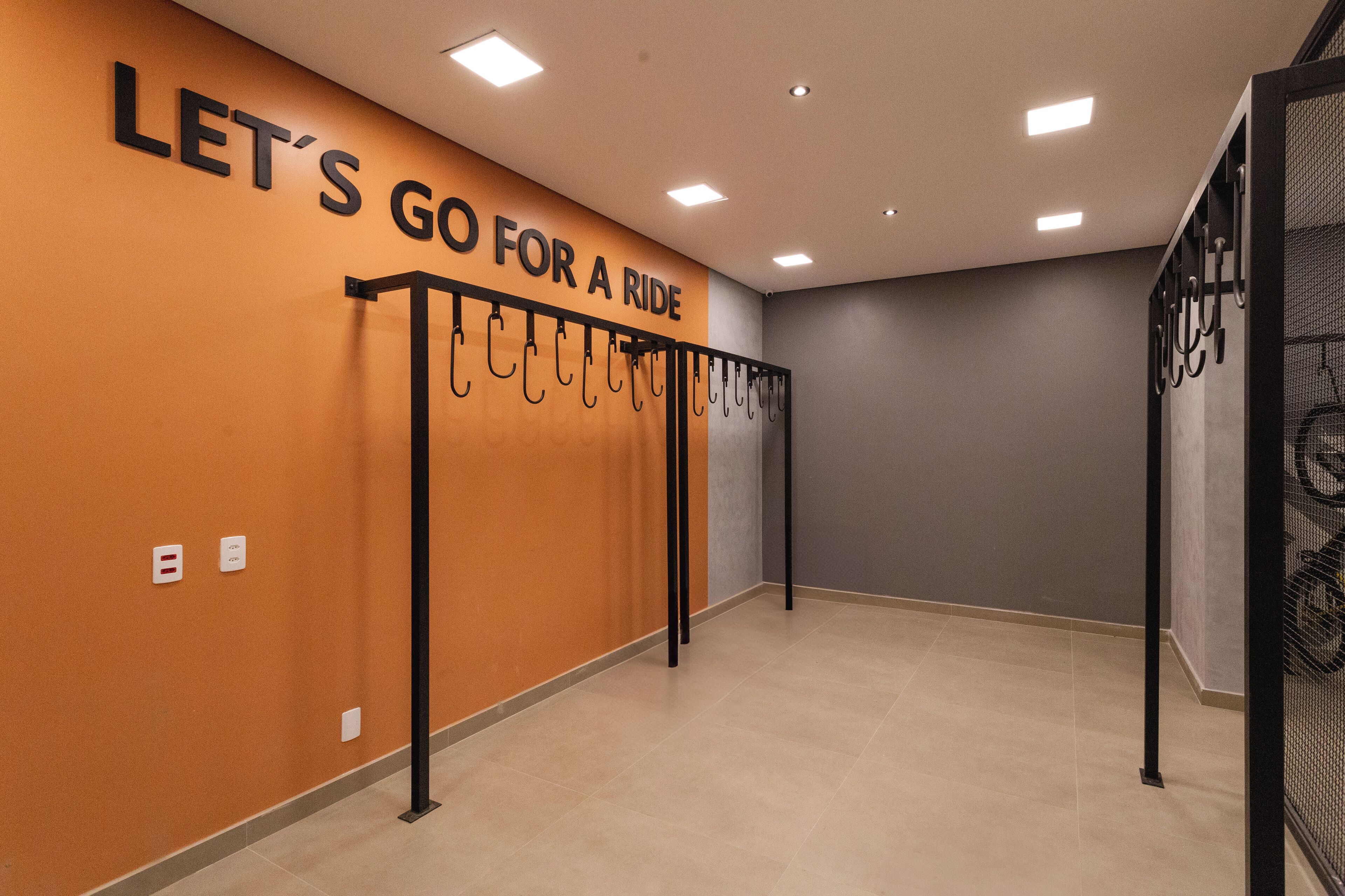A hallway with a wall sign that reads "LET'S GO FOR A RIDE" and a rack with multiple hooks.