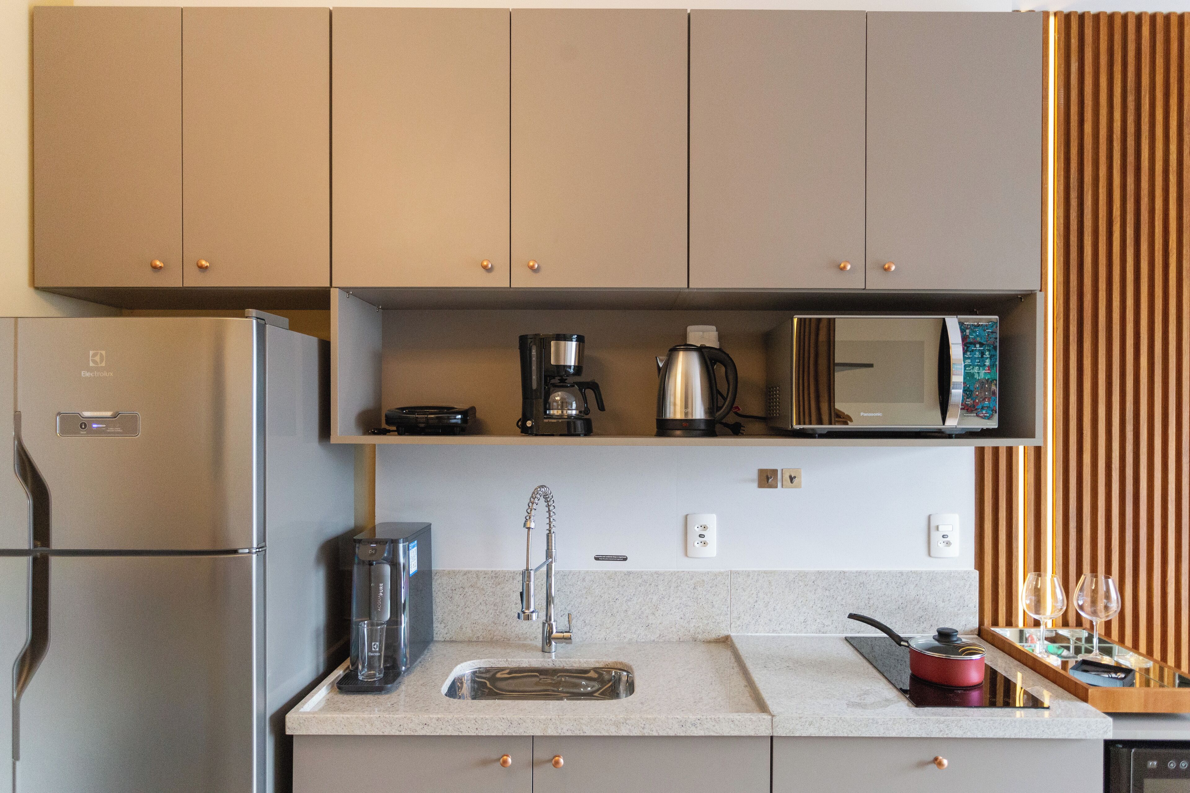A modern kitchen with a built-in refrigerator, a coffee maker, a microwave, and a sink.