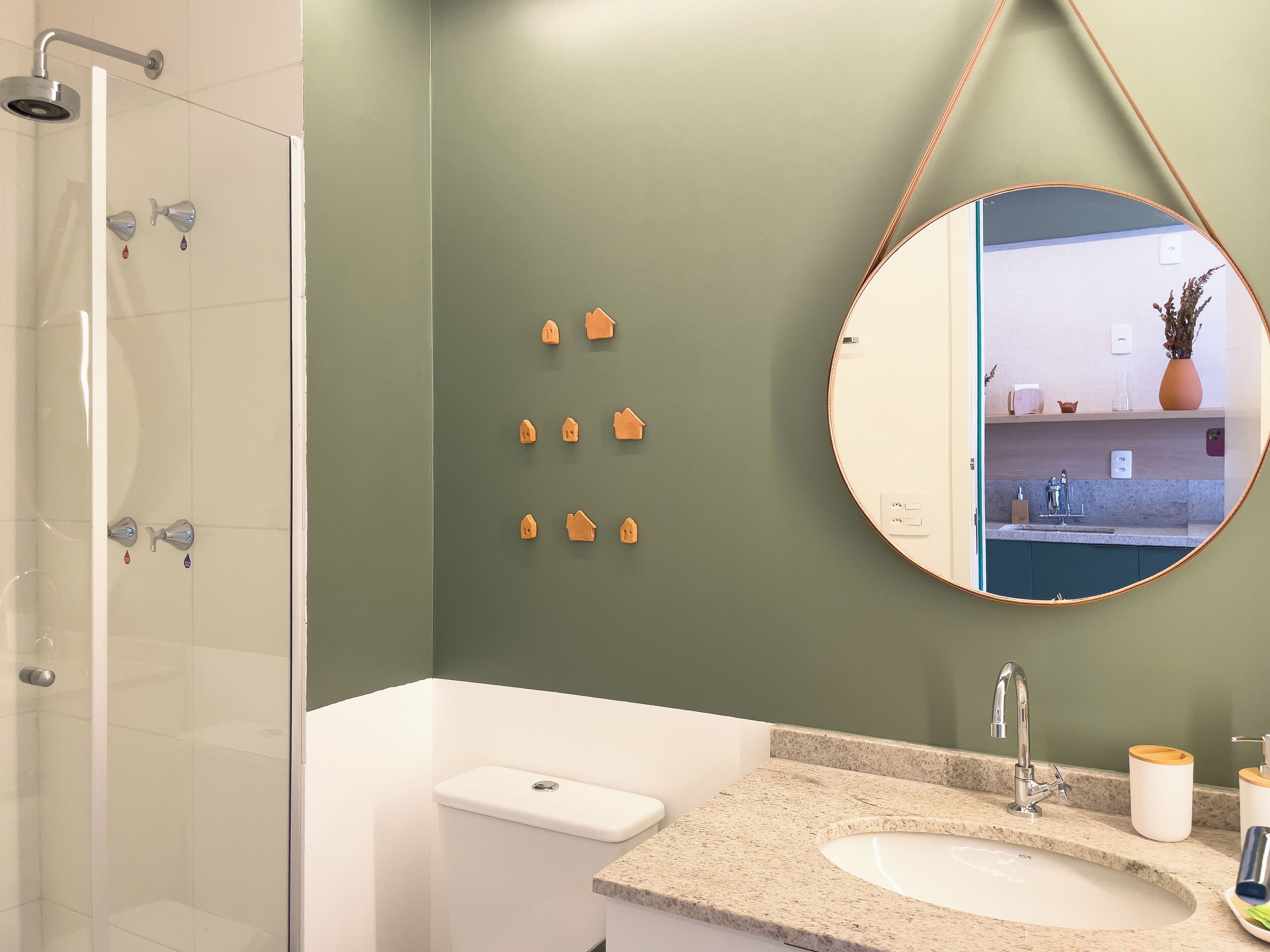 A bathroom with a glass-enclosed shower, a white toilet, a granite countertop sink, and a mirror with a wooden frame.