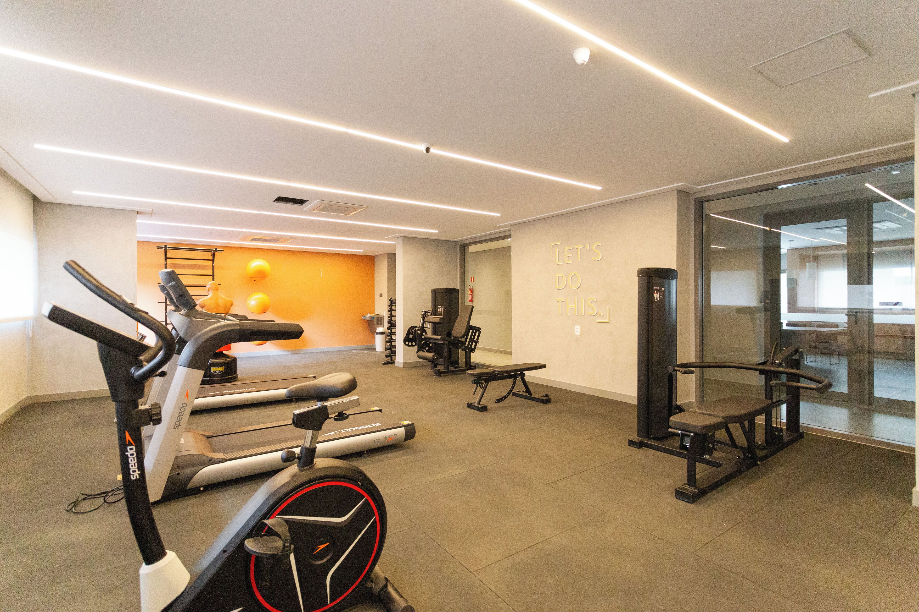 A modern gym with stationary bikes, treadmills, and weight machines.