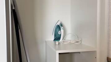 A white shelf with a teal iron and a white power cord.