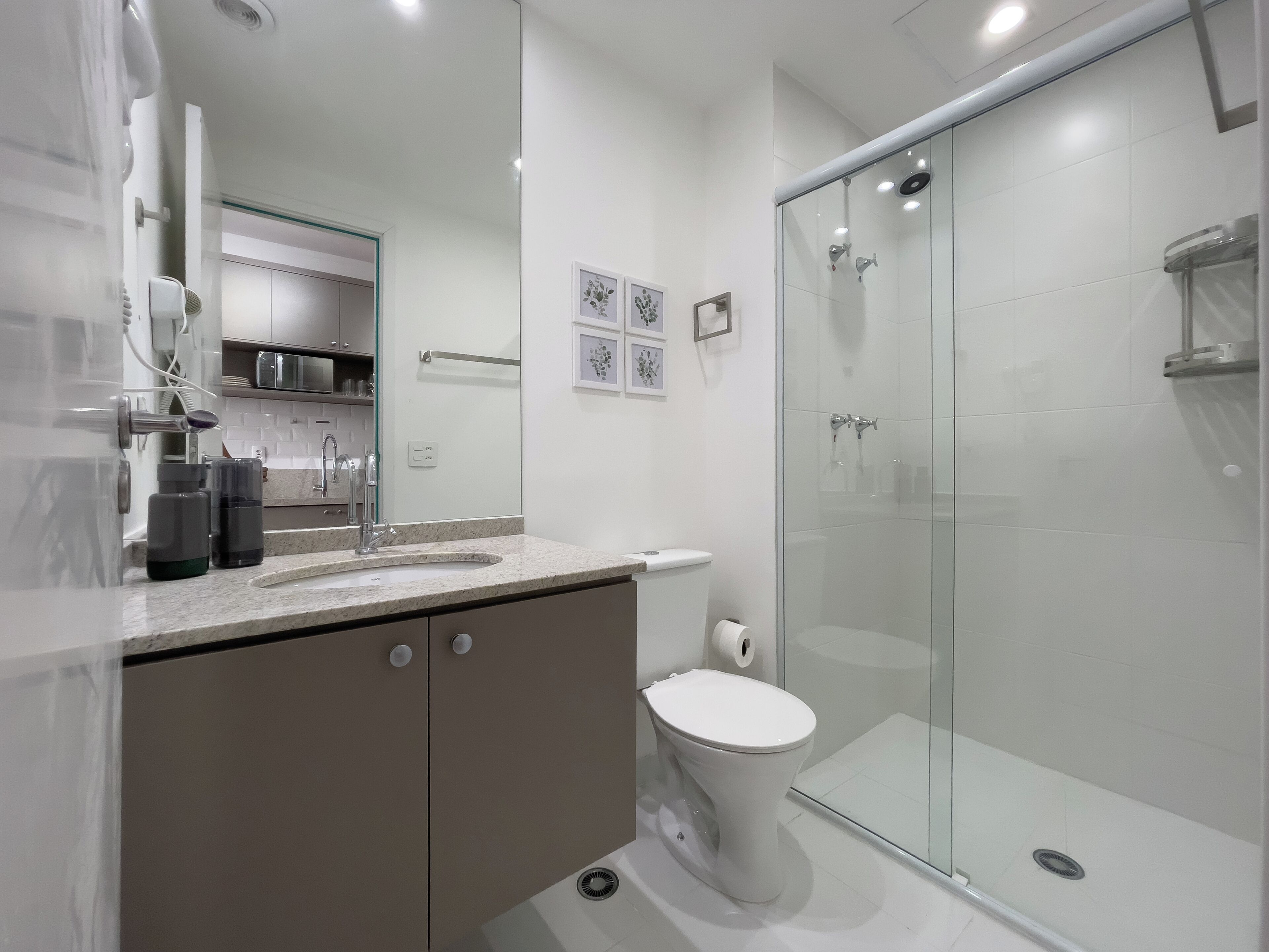 A modern bathroom with a glass-enclosed shower, a white toilet, and a marble countertop.