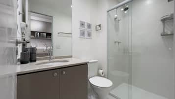 A modern bathroom with a glass-enclosed shower, a white toilet, and a marble countertop.