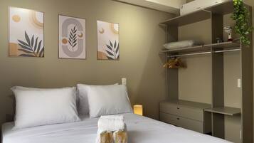 A hotel room with a neatly made bed, a wardrobe, and three wall-mounted artworks.