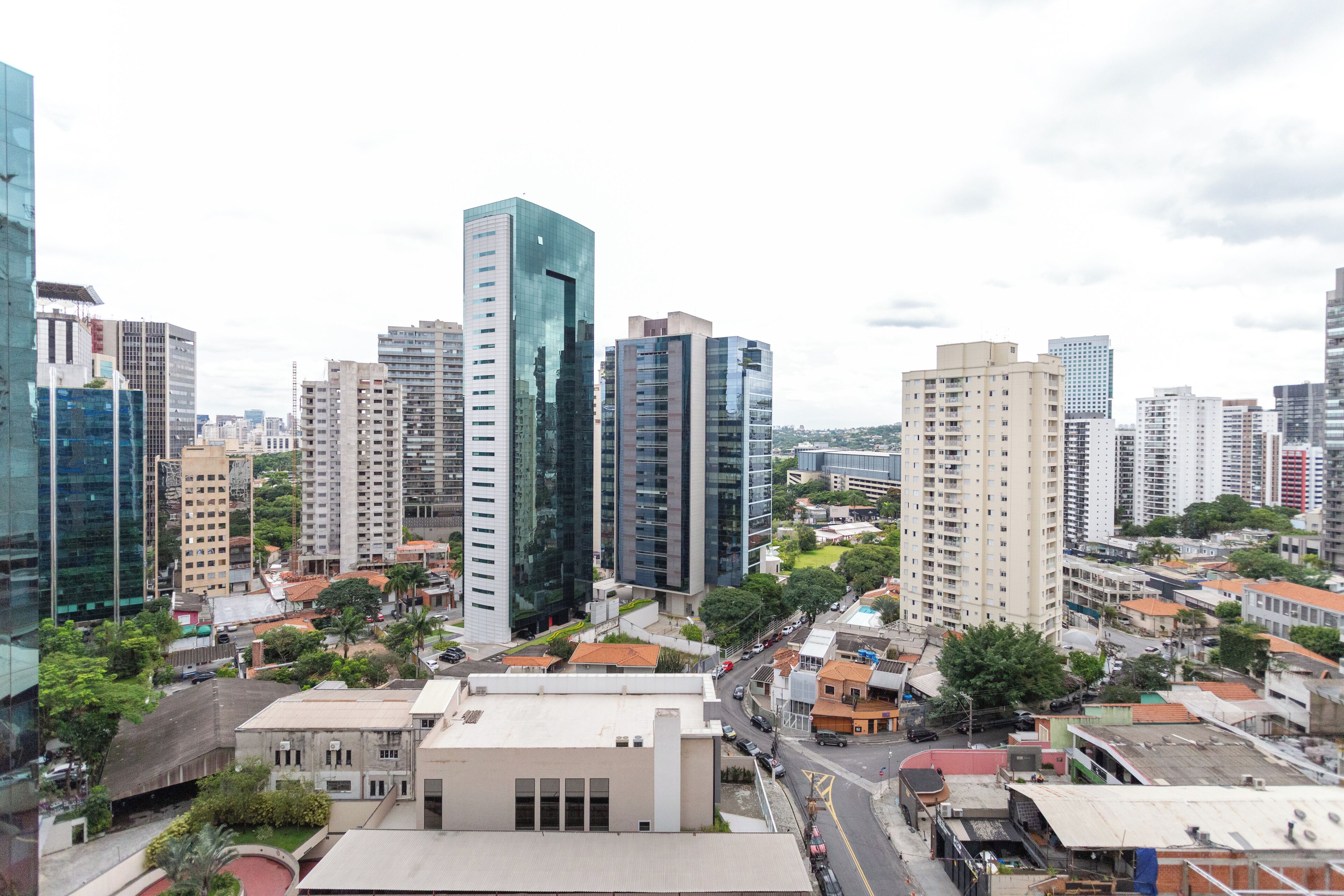 A cityscape with modern high-rise buildings, a mix of residential and commercial structures, and a central road with vehicles.