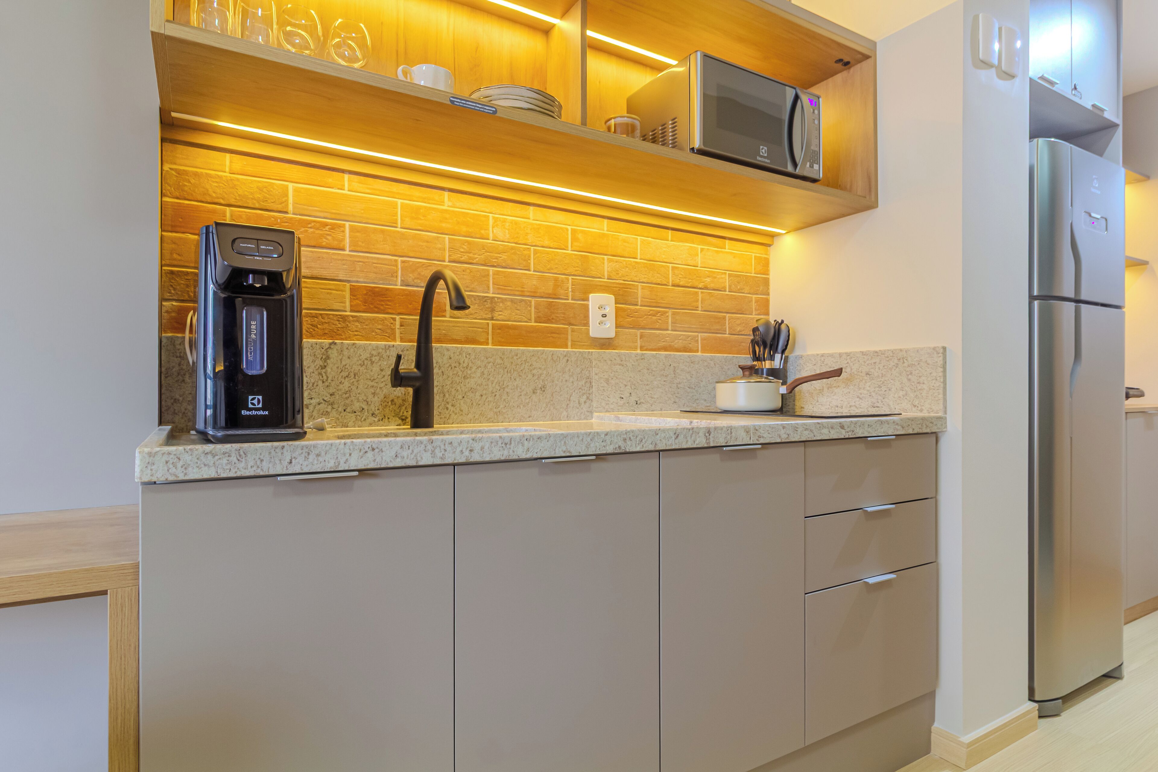 Una cucina moderna con forno a microonde integrato, frigorifero in acciaio inossidabile e macchina da caffè sul piano di lavoro.