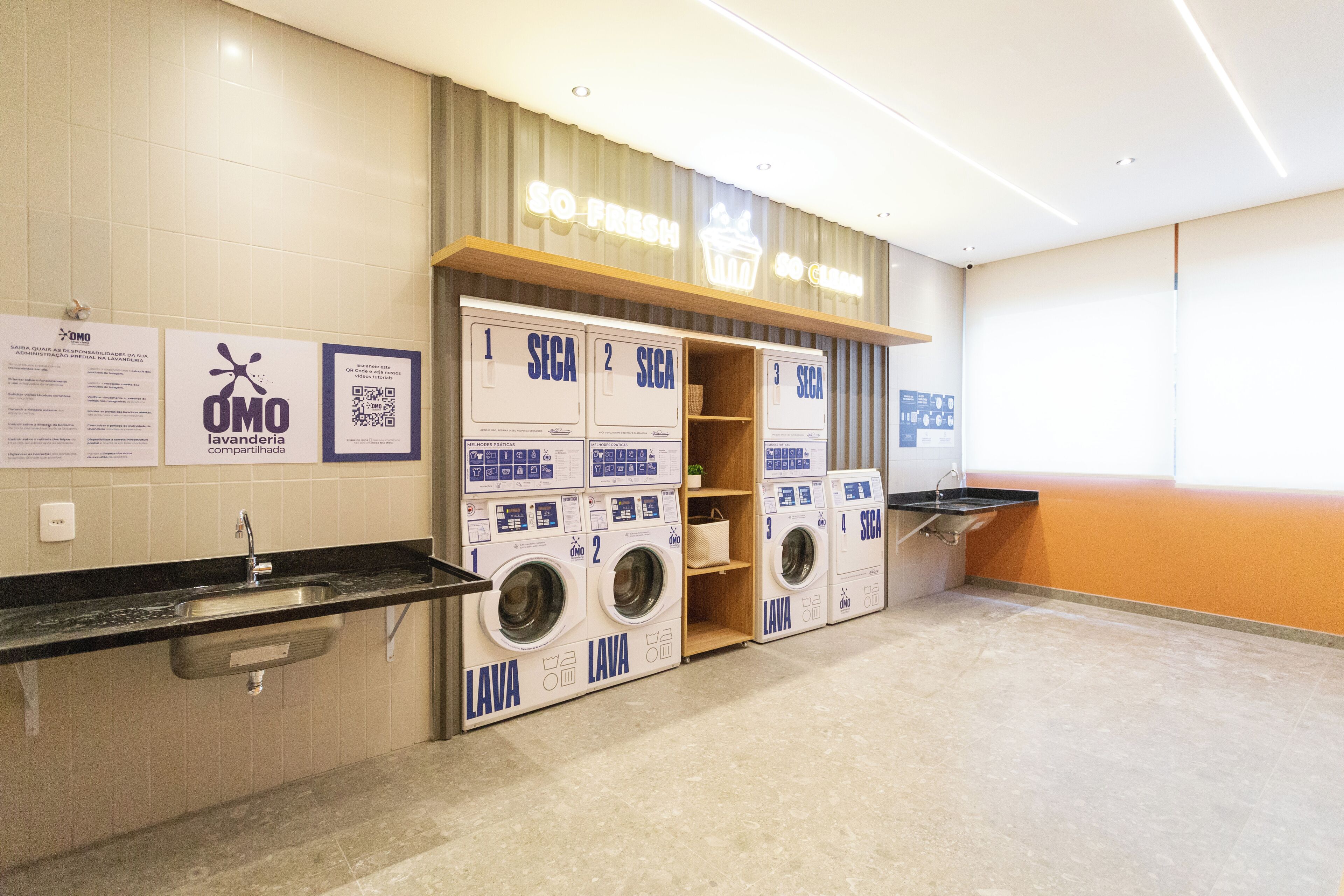 A laundry facility with four washing machines, a sink, and a sign that reads "SO FRESH."