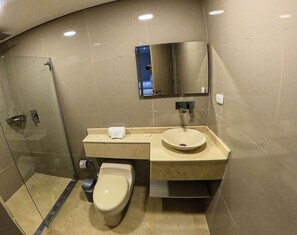 Un baño moderno con cabina de ducha de vidrio, inodoro, lavabo y espejo.