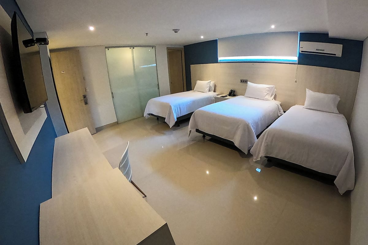 A hotel room with two beds, a desk, a chair, a TV, and a sliding door.