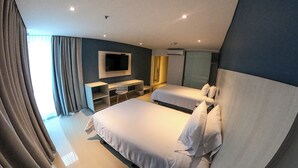 Et moderne hotelværelse med to senge, et skrivebord, en stol, et fjernsyn og et stort vindue med gardiner.