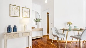 A dining area with a wooden table, chairs, and a vase of flowers. - Locally by Homie in Funchal (Funchal)