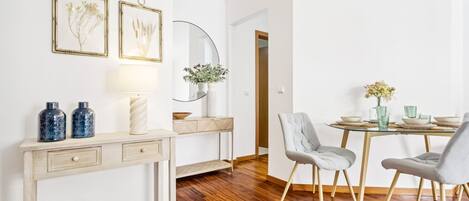 A dining area with a wooden table, chairs, and a vase of flowers.