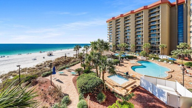 A hotel with a pool, beach view, and multiple balconies.