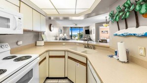 A compact kitchen with a microwave, stove, and sink.