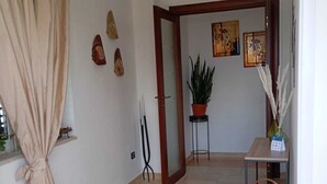 A hallway with a beige curtain, a potted plant, a small table with a basket, and a door leading to another room. - BELVEDERE - Bed & Breakfast - Holiday Home (Pozzilli)