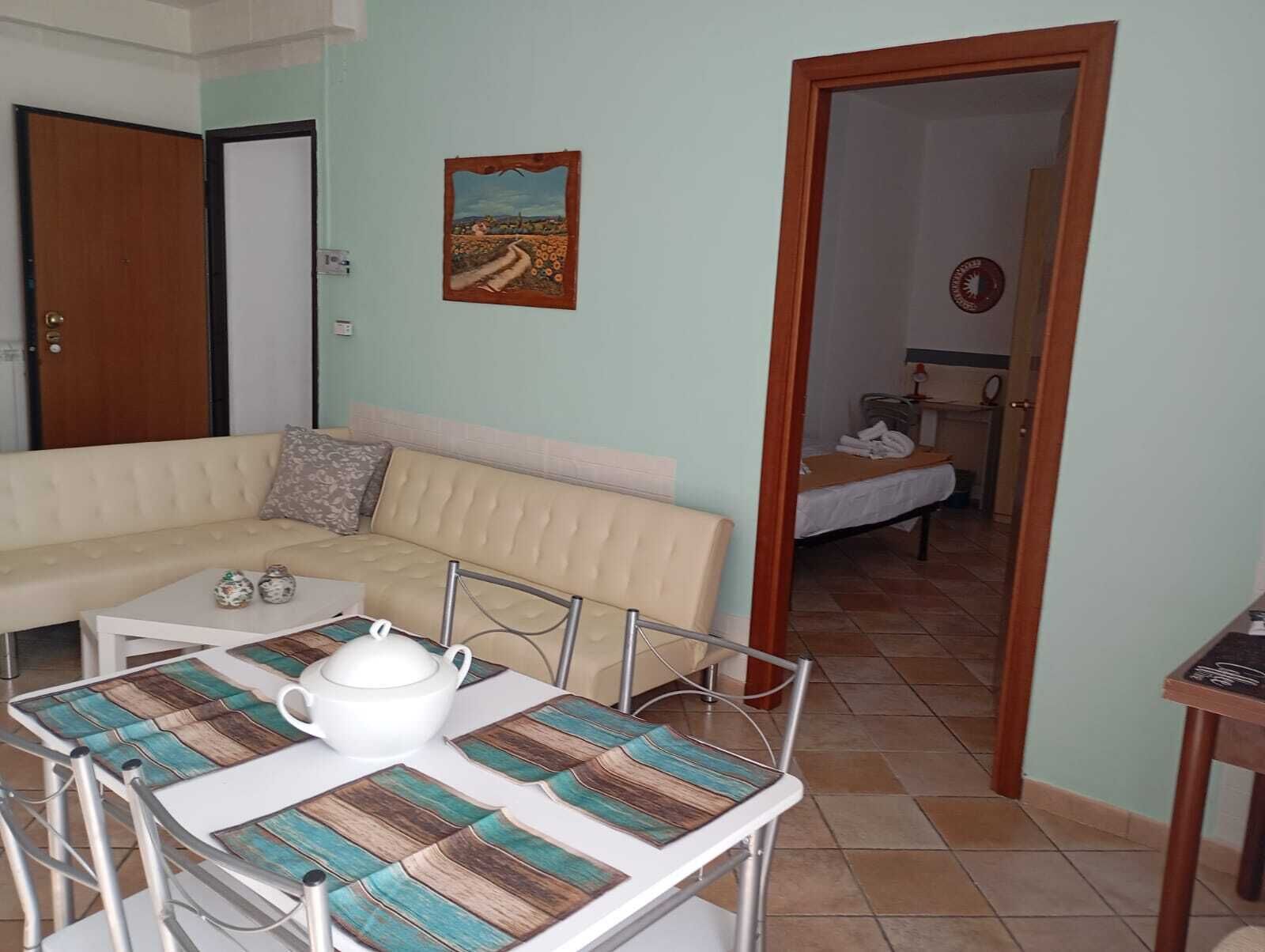 A room with a sofa, a table with a teapot, and a painting on the wall.