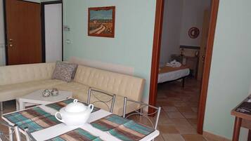 A room with a sofa, a table with a teapot, and a painting on the wall.