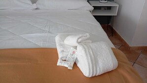 A neatly made bed with white linens and a folded towel on an orange bedspread. - BELVEDERE - Bed & Breakfast - Holiday Home (Pozzilli)