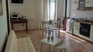 A compact living space with a sofa, a dining table with chairs, a kitchenette with a stove, a microwave, and a television mounted on the wall. - BELVEDERE - Bed & Breakfast - Holiday Home (Pozzilli)