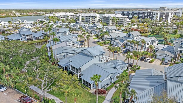 A residential area with multiple two-story houses, a large body of water, and a distant view of a city skyline. - Gulf & Bay Club Bayside | Walk to Beach, Enjoy Pools, Tennis & More (Siesta Key)