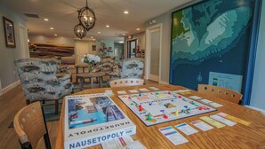 A dining area with a wooden table set for a board game, surrounded by patterned chairs. - Brewster Green Resort  (Brewster)