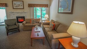 A cozy living room with a fireplace, two sofas, a coffee table, and a lamp. - Brewster Green Resort  (Brewster)