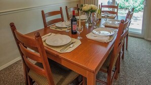 A dining room with a wooden table set for six, surrounded by chairs, a chandelier, and a framed picture on the wall. - Brewster Green Resort  (Brewster)