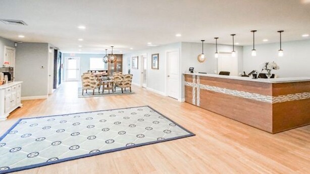 A hotel lobby with a reception desk, a dining area, and a patterned rug on the floor. - Brewster Green Resort  (Brewster)