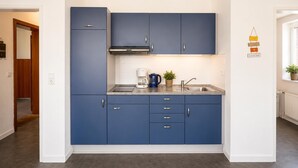 A modern kitchen with blue cabinets, a stainless steel sink, and a coffee maker. - House Najade, small feel-good oasis Whg. 7, Pastoratsweg 17, 27476 Cuxhaven Döse (Cuxhaven)