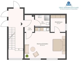 A floor plan of a residential property with a living room, kitchen, bathroom, and two bedrooms. The living room is centrally located with a sofa and a coffee table. The kitchen is adjacent to the living room with a dining area. The bathroom is located near the kitchen, and there are two bedrooms, one with a larger space. - House Najade, small feel-good oasis Whg. 7, Pastoratsweg 17, 27476 Cuxhaven Döse (Cuxhaven)