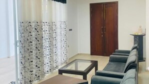 A modern living room with a chandelier, a dining table, sofas, and a clock on the wall. - Hotel Ceylonia Colombo (Colombo)