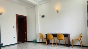 A room with a dining table and four chairs, a wooden door, and two wall-mounted lights. - Hotel Ceylonia Colombo (Colombo)