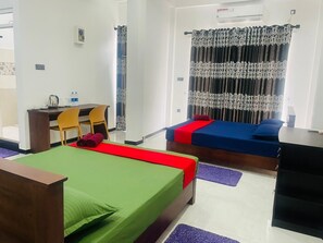 Habitación de hotel con dos camas individuales, un escritorio con sillas, dispensador de agua y una ventana con cortinas.