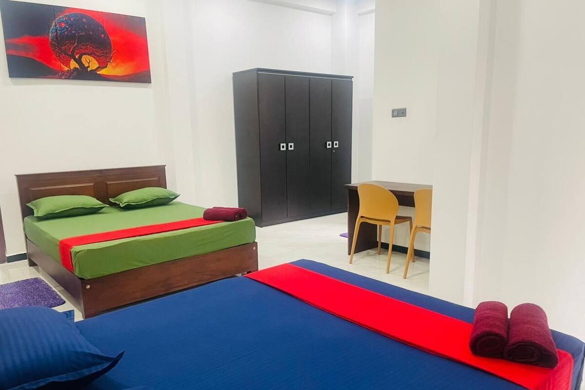 A bedroom with a bed, a desk, and a wardrobe.