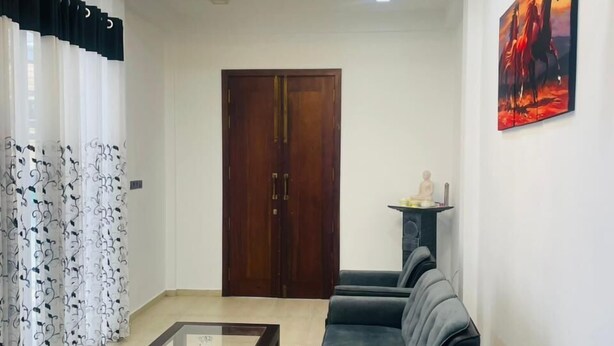 A modern living room with a chandelier, a sofa set, a coffee table, and a clock on the wall. - Hotel Ceylonia Colombo (Colombo)