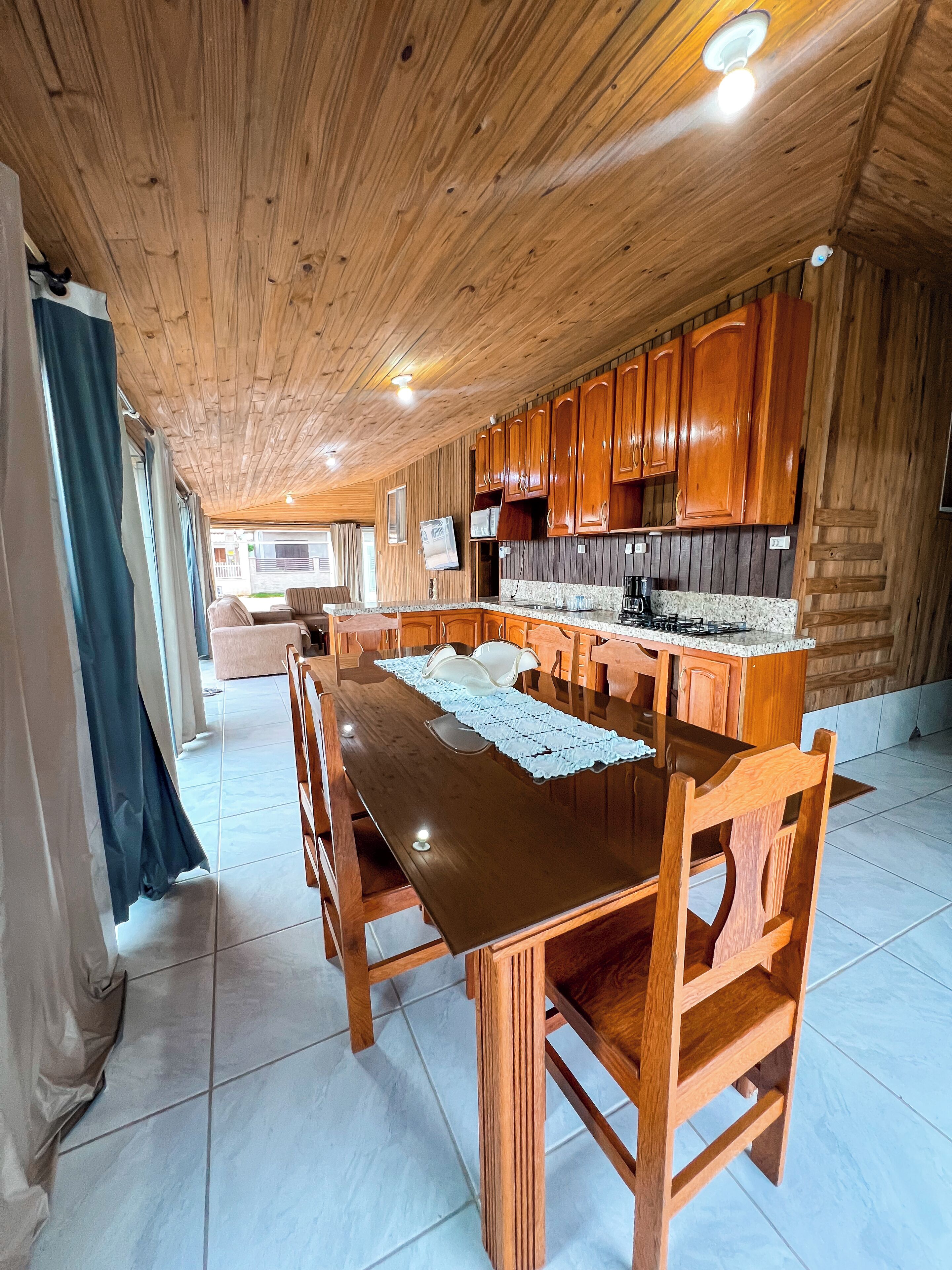 Una cocina con paneles de madera, una isla central, armarios de madera y piso de baldosas.