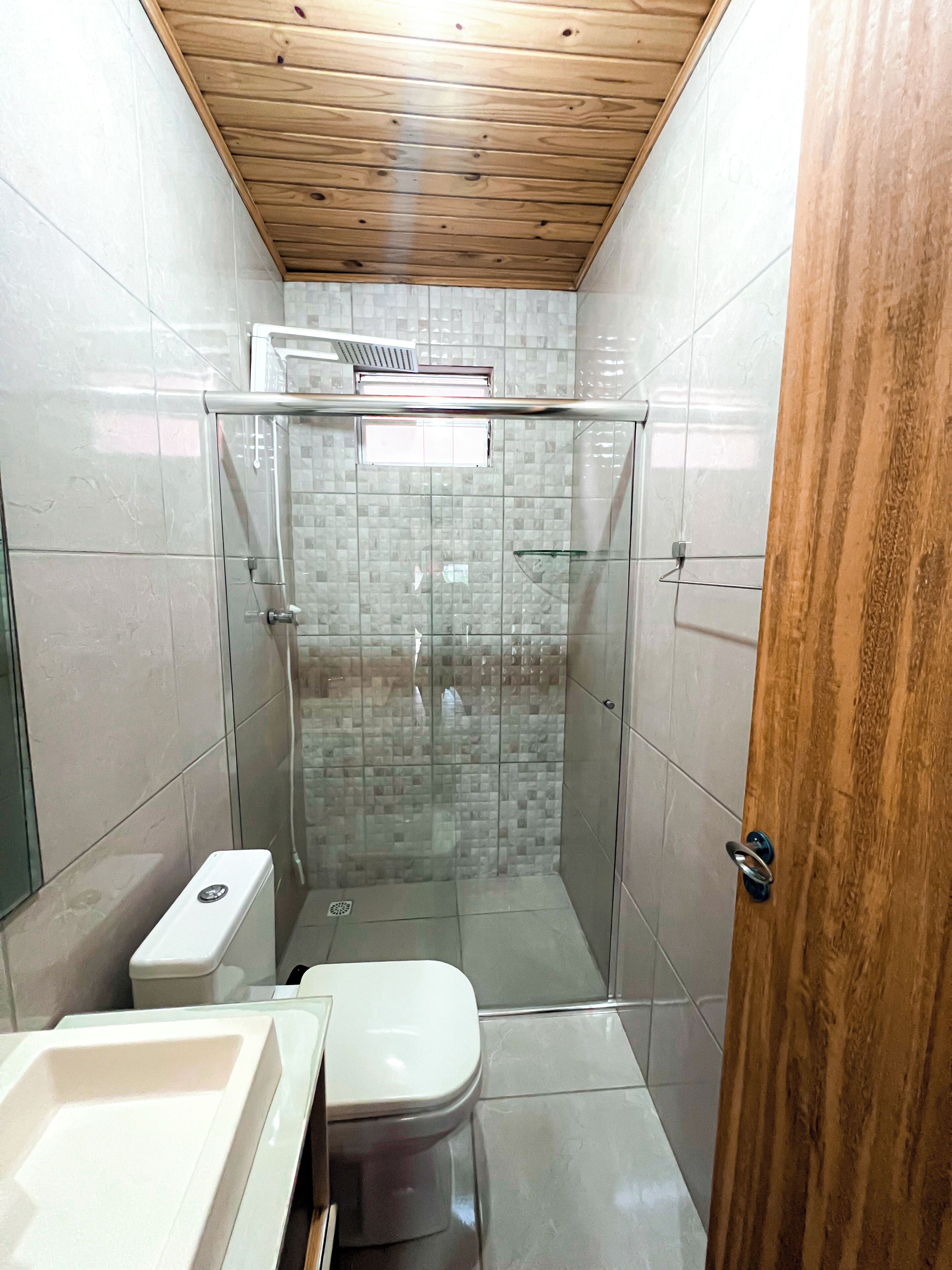 A small bathroom with a shower, toilet, and sink.