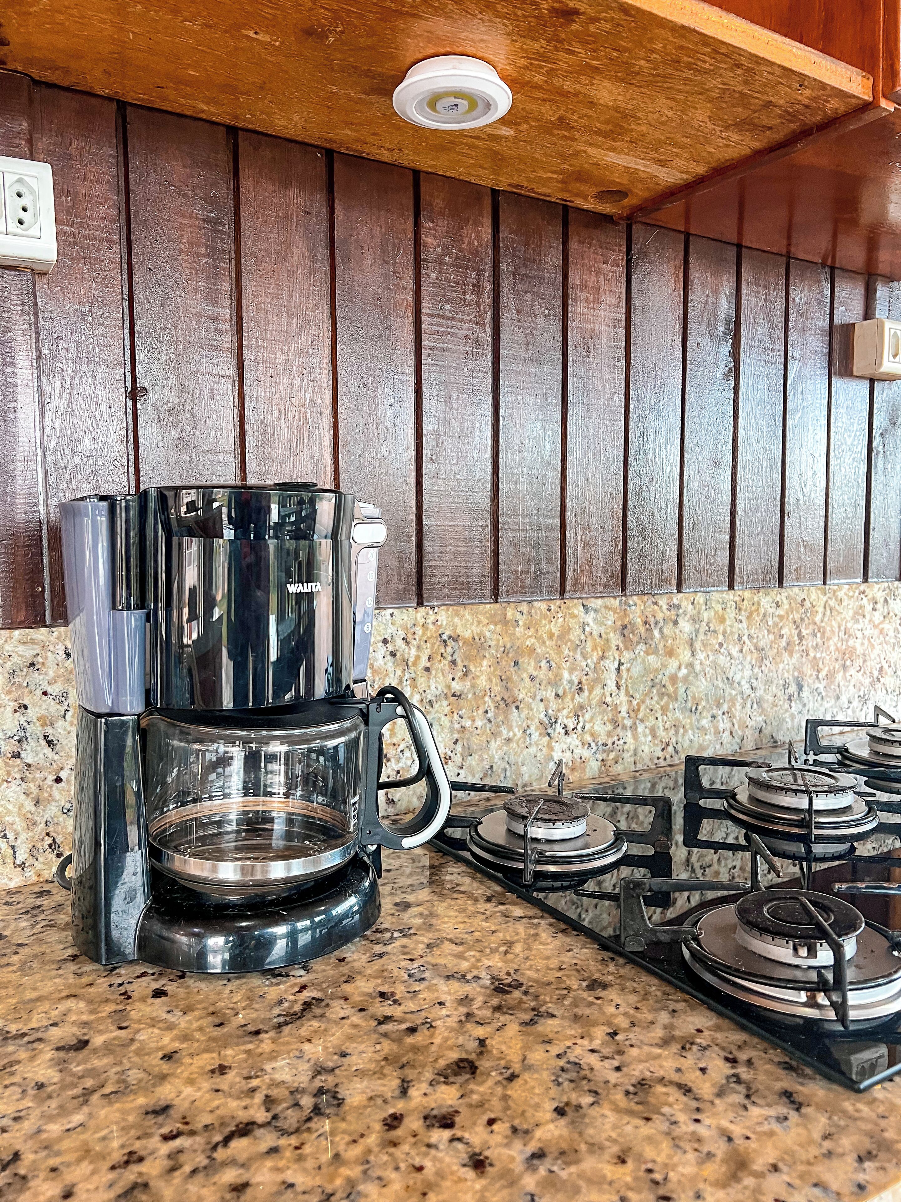 Una cocina con cafetera, estufa a gas y pared de madera.