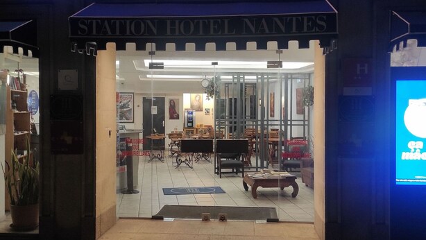 L’entrée de l’hôtel de la Gare se distingue par son intérieur moderne, avec des meubles en bois et une porte en verre.