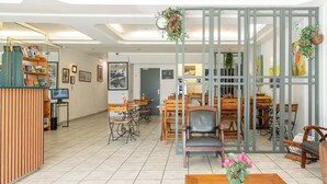 Un espace d’accueil comprenant un bureau en bois, des chaises, un ordinateur et un mur orné de tableaux et d’une horloge.