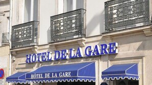 L’extérieur de l’HÔTEL DE LA GARE, avec son auvent bleu et une enseigne au-dessus de l’entrée.
