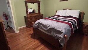 A bedroom with a wooden bed, a dresser, a mirror, and a ceiling light. - Charming 3-bedroom house in Mountain City beautiful big coy pond in backyard (Mountain City)